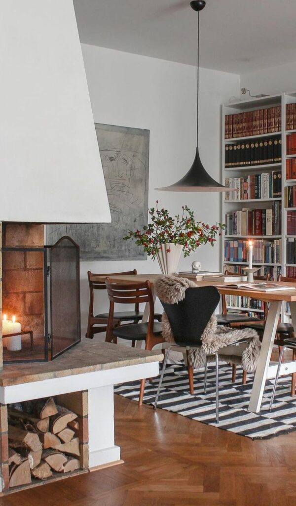 Il caminetto è protagonista nella sala da pranzo, con il grande tavolo accanto alla libreria a tutta parete