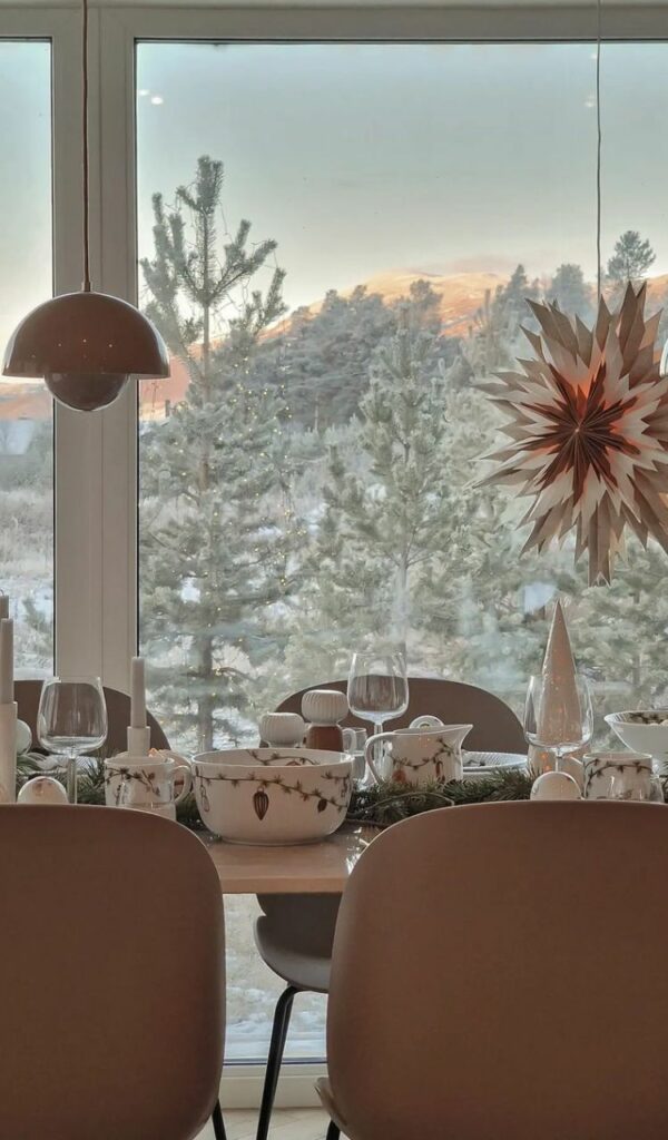 Una tavola imbandita con un paesaggio innevato da favola dietro alla finestra