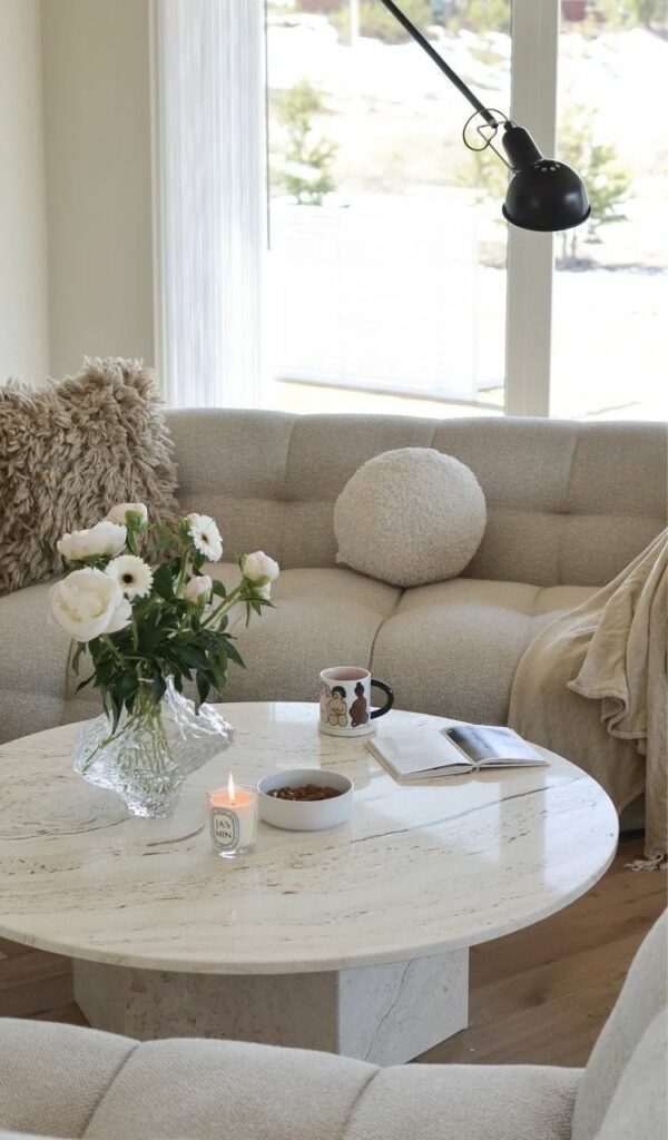 Un tavolino tondo in marmo tra i due divani écru del living