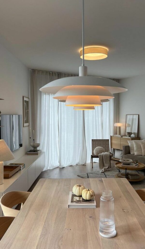 Una grande finestra schermata dalle tende bianche illumina il salone improntato sul più raffinato minimalismo nordico