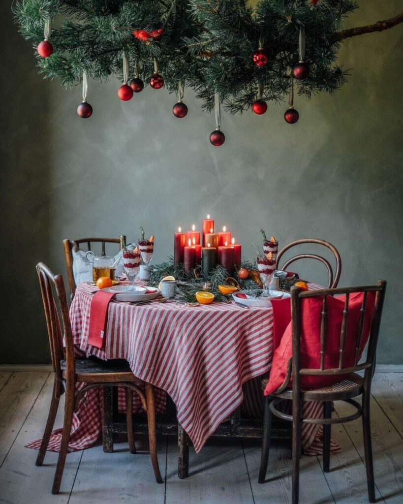 Una tavola di Natale gioiosa con tovaglia a righe bianche e rosse, candele e frutta di stagione