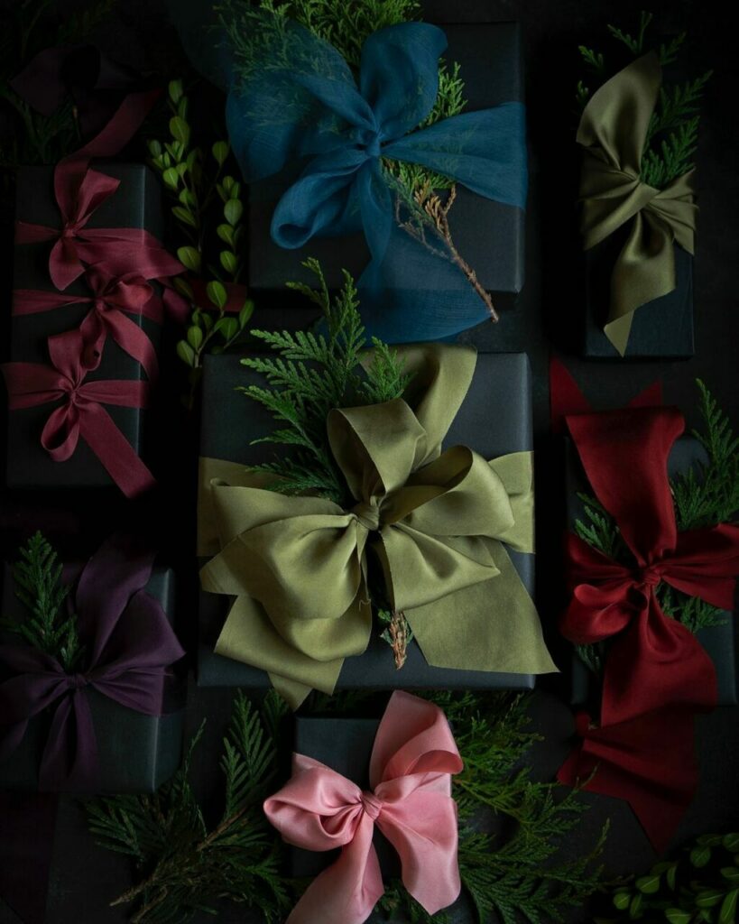 Pacchetti regalo chiusi da grandi fiocchi di seta tinta con colori naturali 