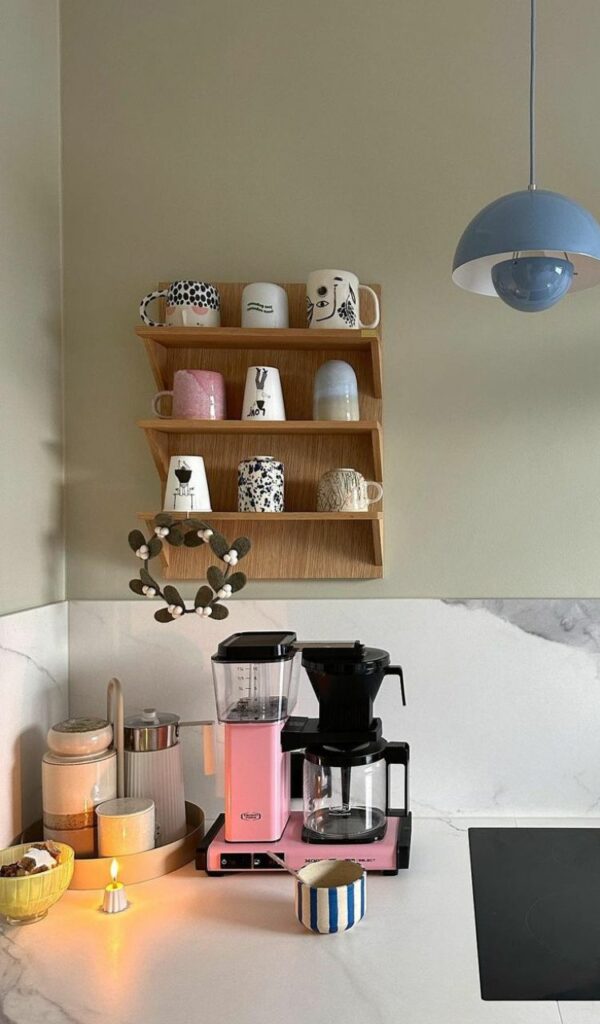 La macchina del caffè rosa sullo sfondo neutro del piano di lavoro in cucina