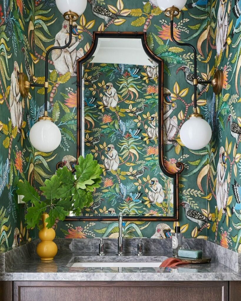 Una wallpaper jungle style, due lampade oversize e uno specchio dallo stile orientaleggiante