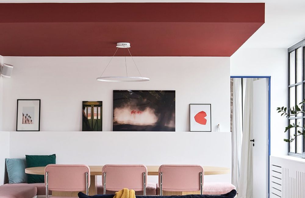 Un soffitto colorato di rosso delimita la zona pranzo in un ambiente open space