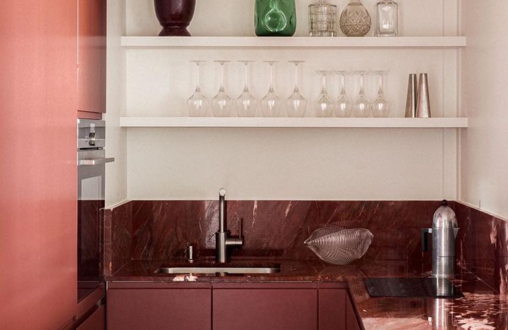 Una cucina piccola ma elegante, dominata dal rosso dei frontali laccati e del marmo